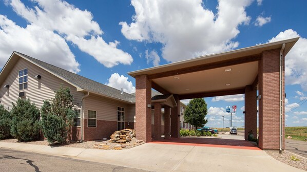 A building with a covered entrance, a brick facade, and a clear sky.