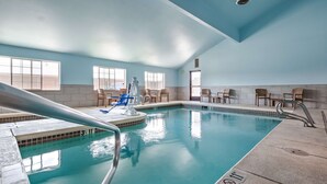 An indoor swimming pool with clear water, surrounded by lounge chairs and a lifeguard chair. - Best Western Rambler (Walsenburg)