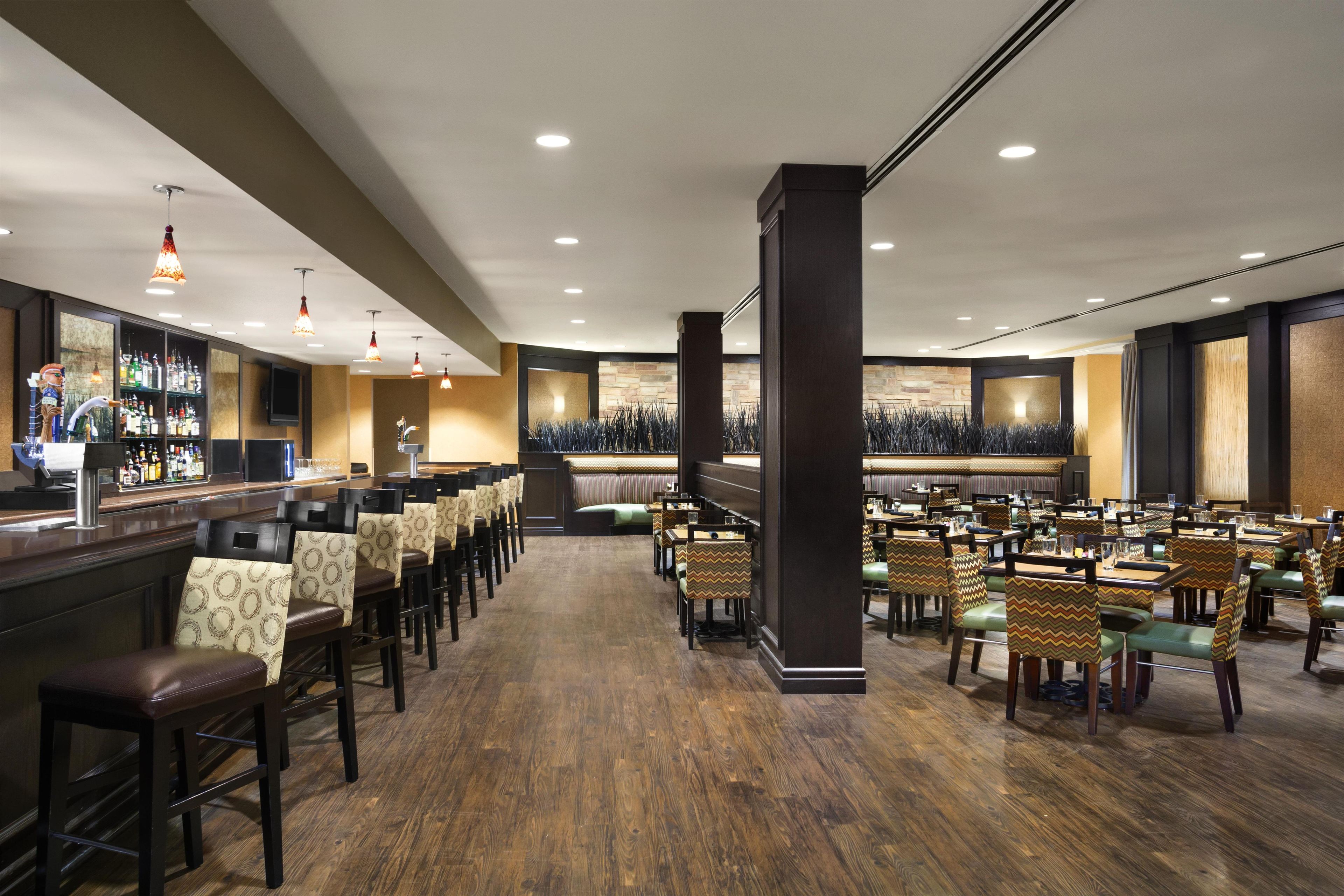 A hotel lobby with a bar area, seating arrangements, and a central pillar.