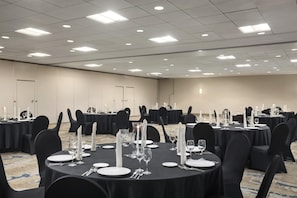 A conference room with multiple tables set for dining, equipped with chairs, plates, cutlery, and glassware. - DoubleTree by Hilton Dallas - DFW Airport North (Irving)