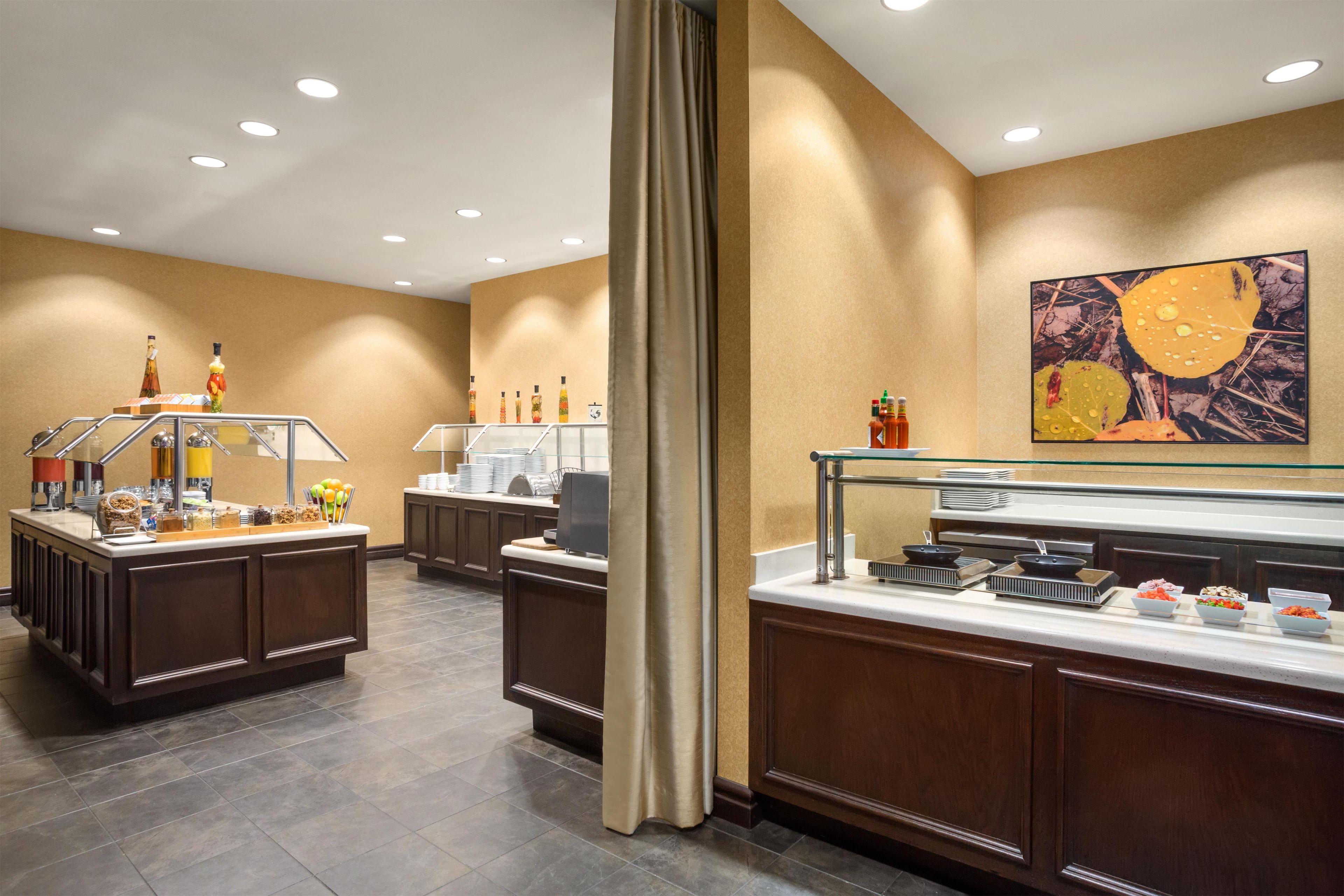 A buffet area with a variety of food options, including fruits, condiments, and hot dishes.