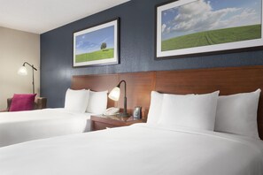 A hotel room with two beds, a nightstand, a lamp, a phone, and a coffee maker. - DoubleTree by Hilton Dallas - DFW Airport North (Irving)