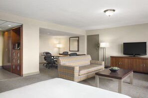 A hotel room with a bed, a sofa, a desk with a chair, a television, and a cabinet. - DoubleTree by Hilton Dallas - DFW Airport North (Irving)