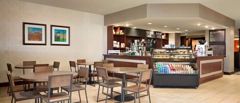 A restaurant area with tables and chairs, a counter with a display case, and a menu board.
