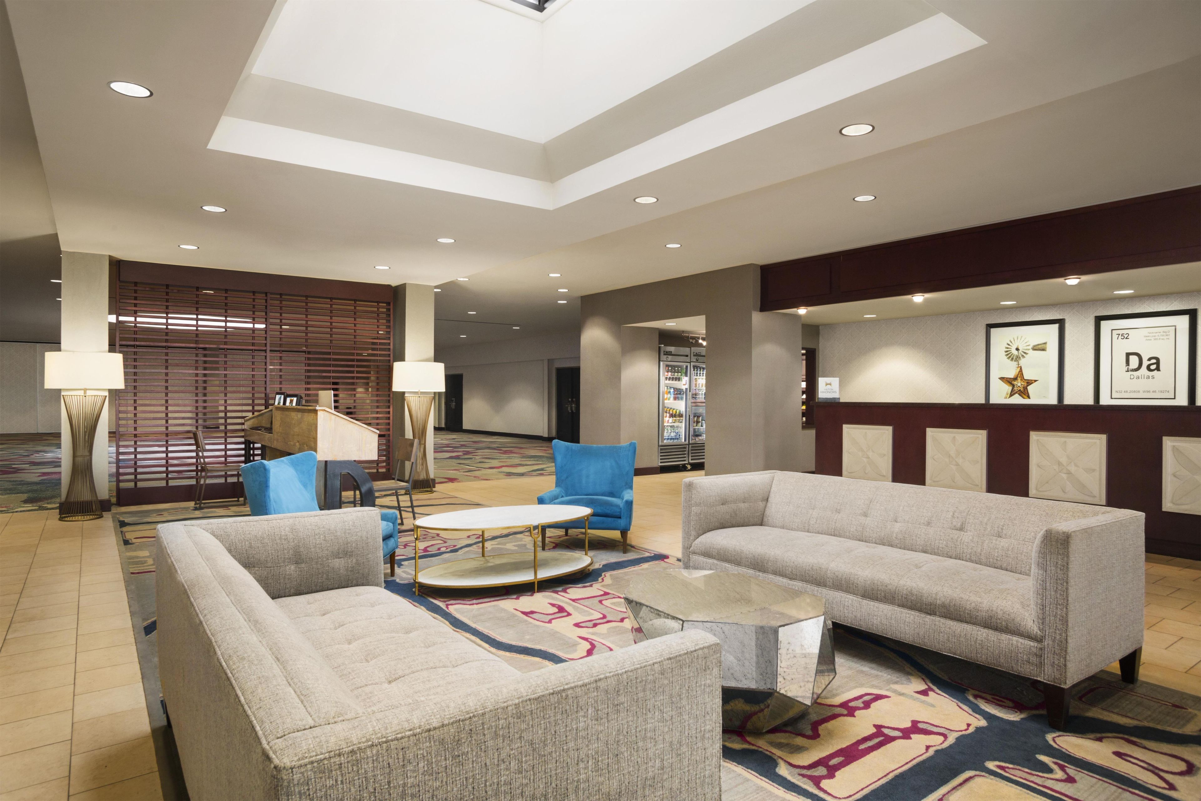 A hotel lobby with seating areas, a reception desk, and a wall with framed pictures.
