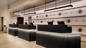A reception area with modern black reception desks, wooden panel walls, and pendant lighting. - Santa Clara Marriott (Santa Clara)