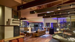 A spacious living area with a sofa, coffee table, and a buffet counter with various food items. - Santa Clara Marriott (Santa Clara)