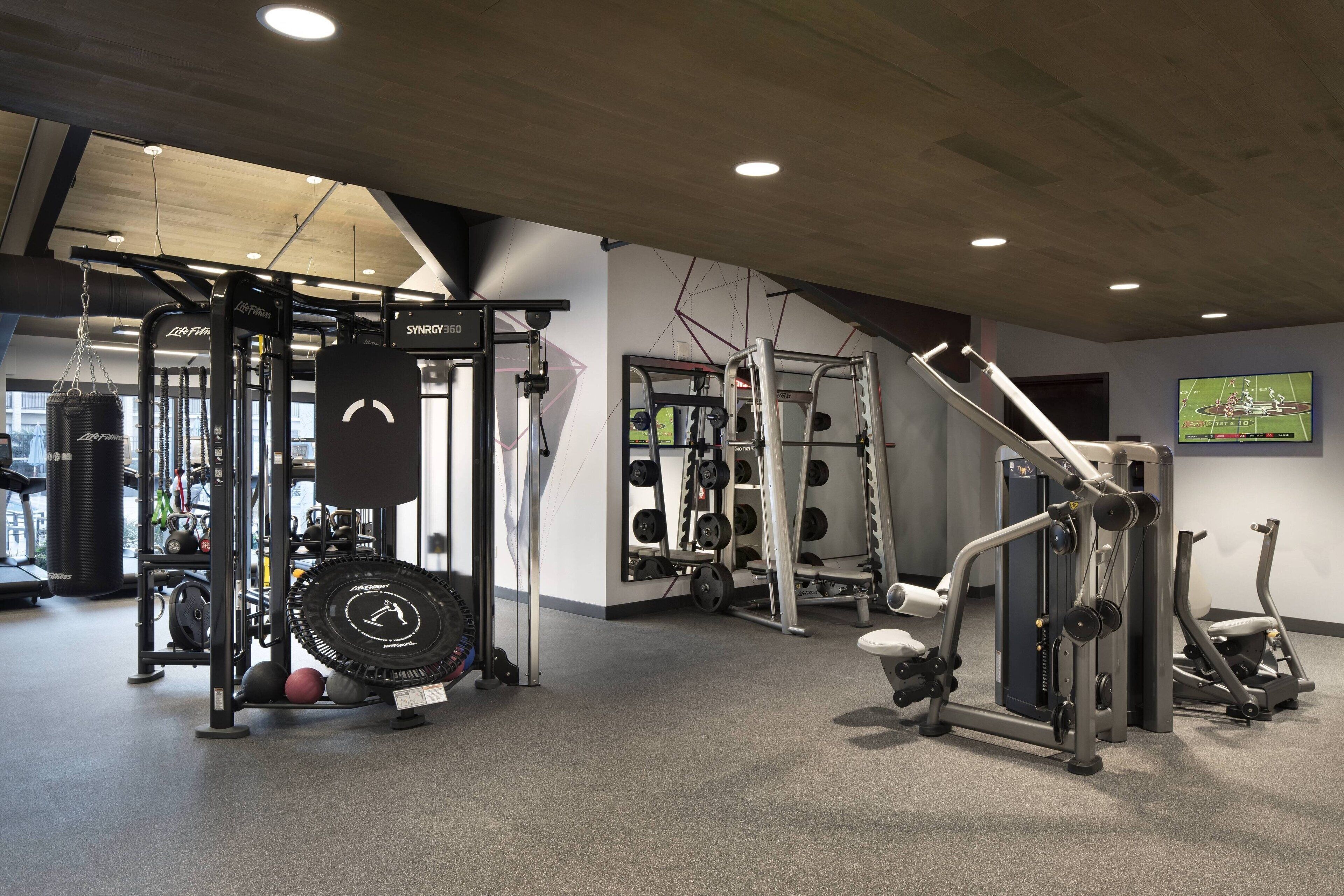 A gym with various exercise equipment, including weight machines, a pull-up bar, and a treadmill.