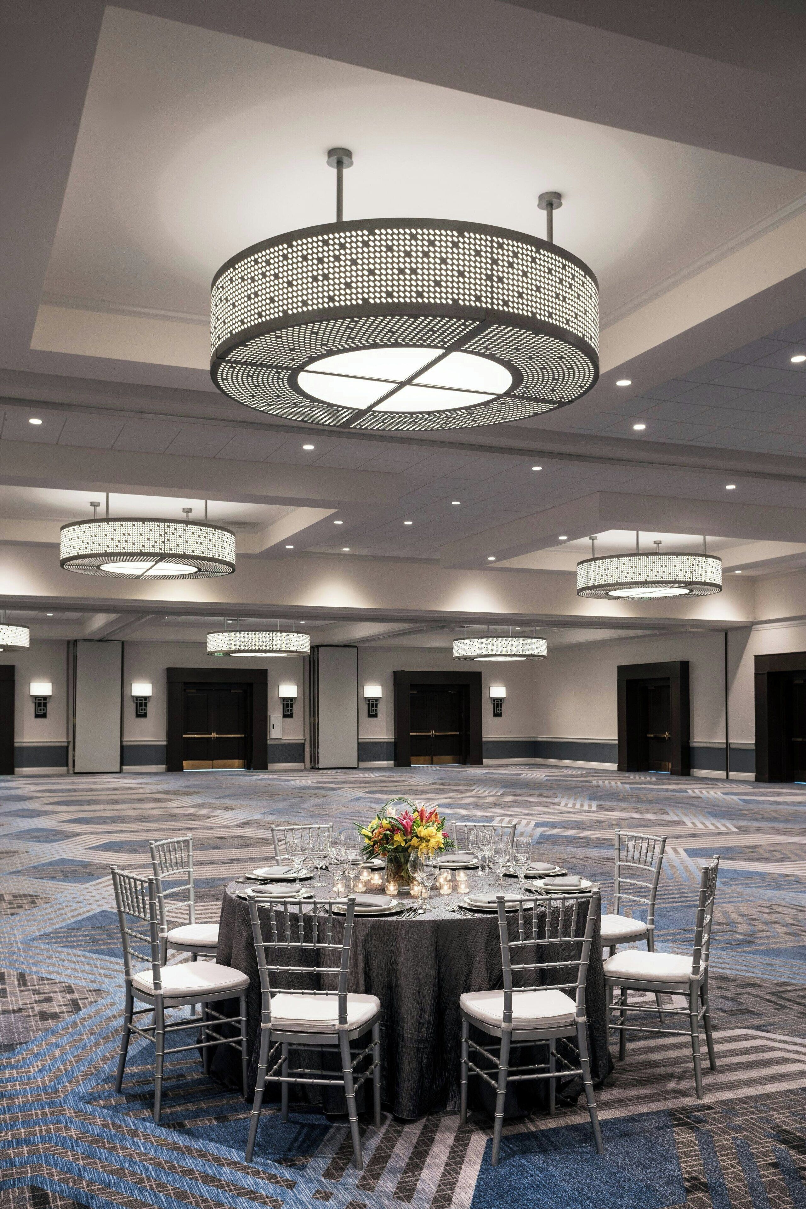 Un salón de banquetes con mesas redondas, sillas y candelabros.