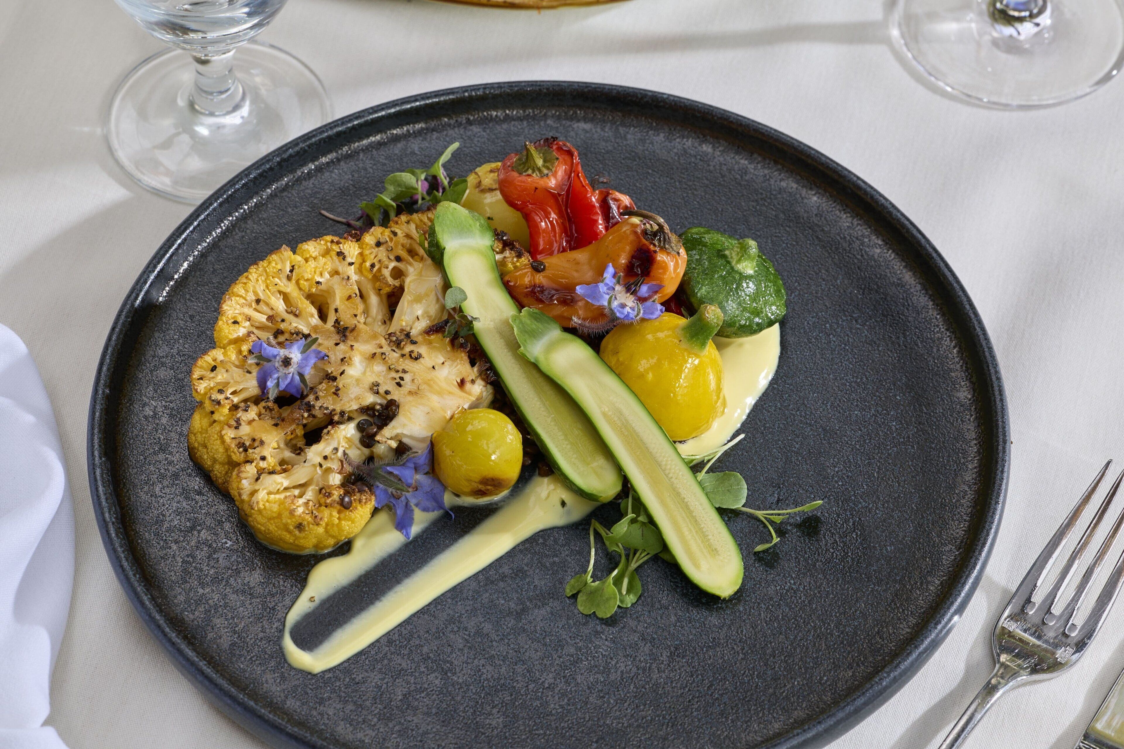 Une assiette de nourriture comprenant des légumes grillés et une sauce.