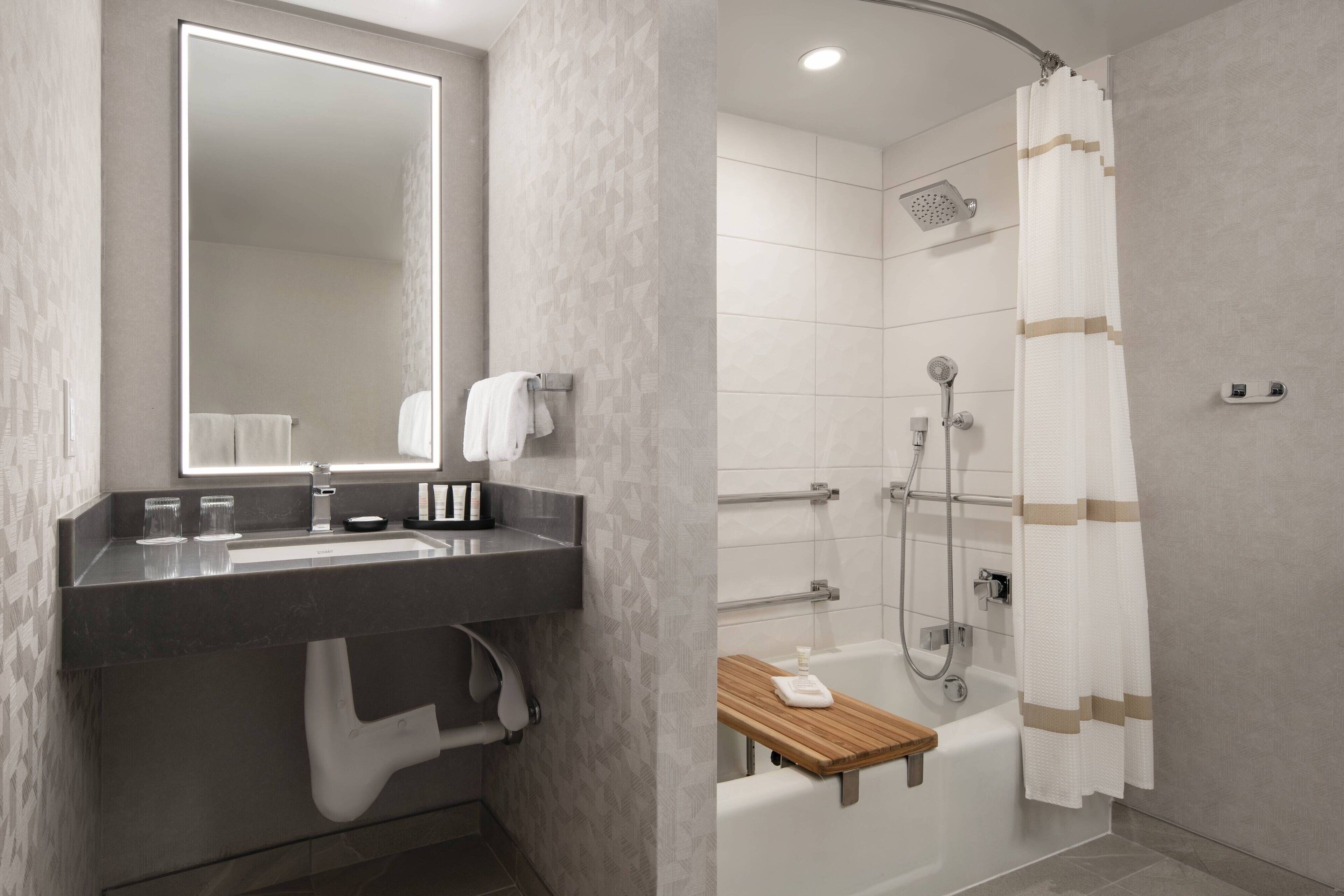 Un baño moderno con un espejo grande, un lavamanos, un inodoro y una zona de ducha.