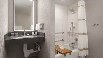 Un baño moderno con un espejo grande, un lavamanos, un inodoro y una zona de ducha.