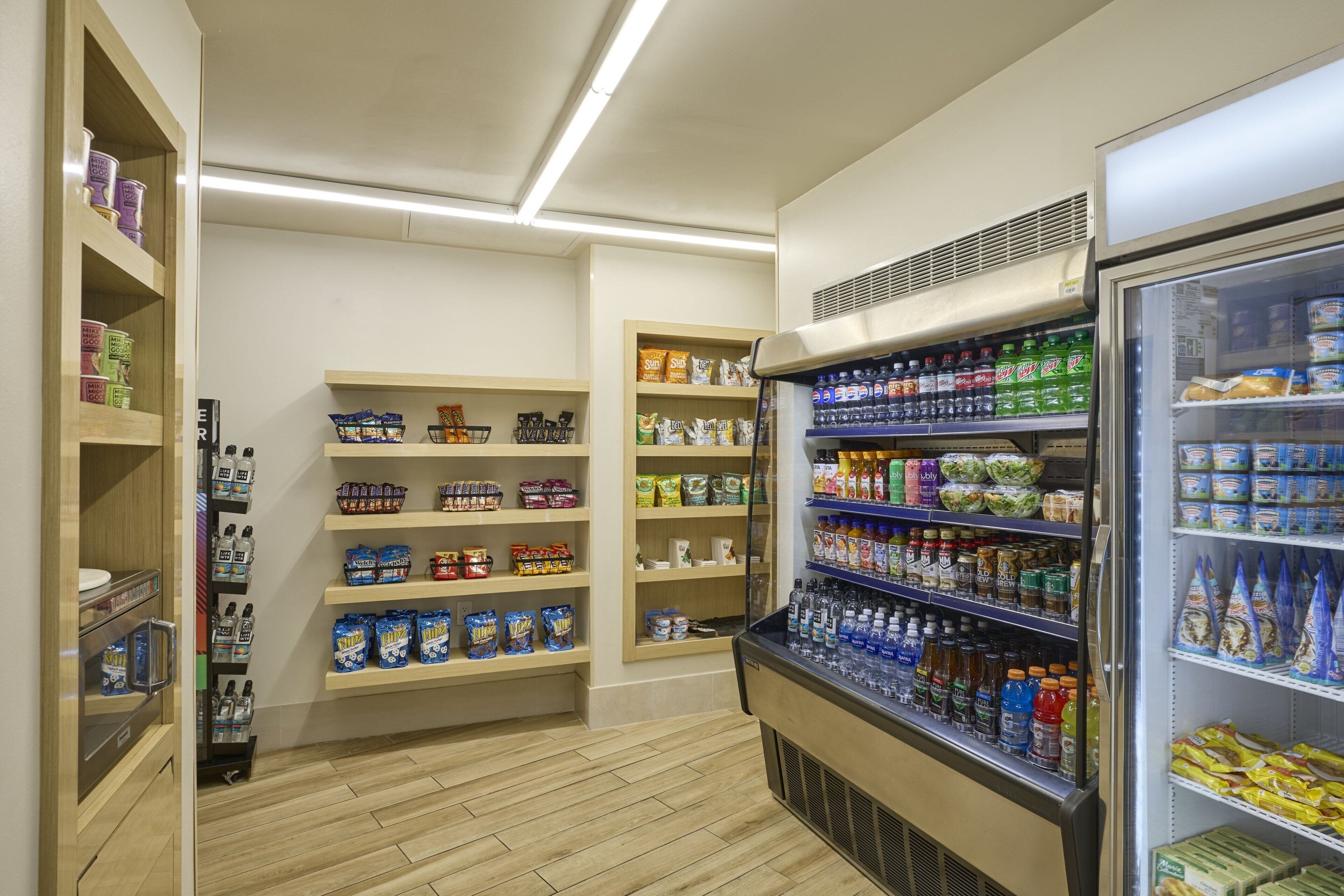 A clean, well-organized grocery store with shelves stocked with various products including snacks, beverages, and packaged foods.