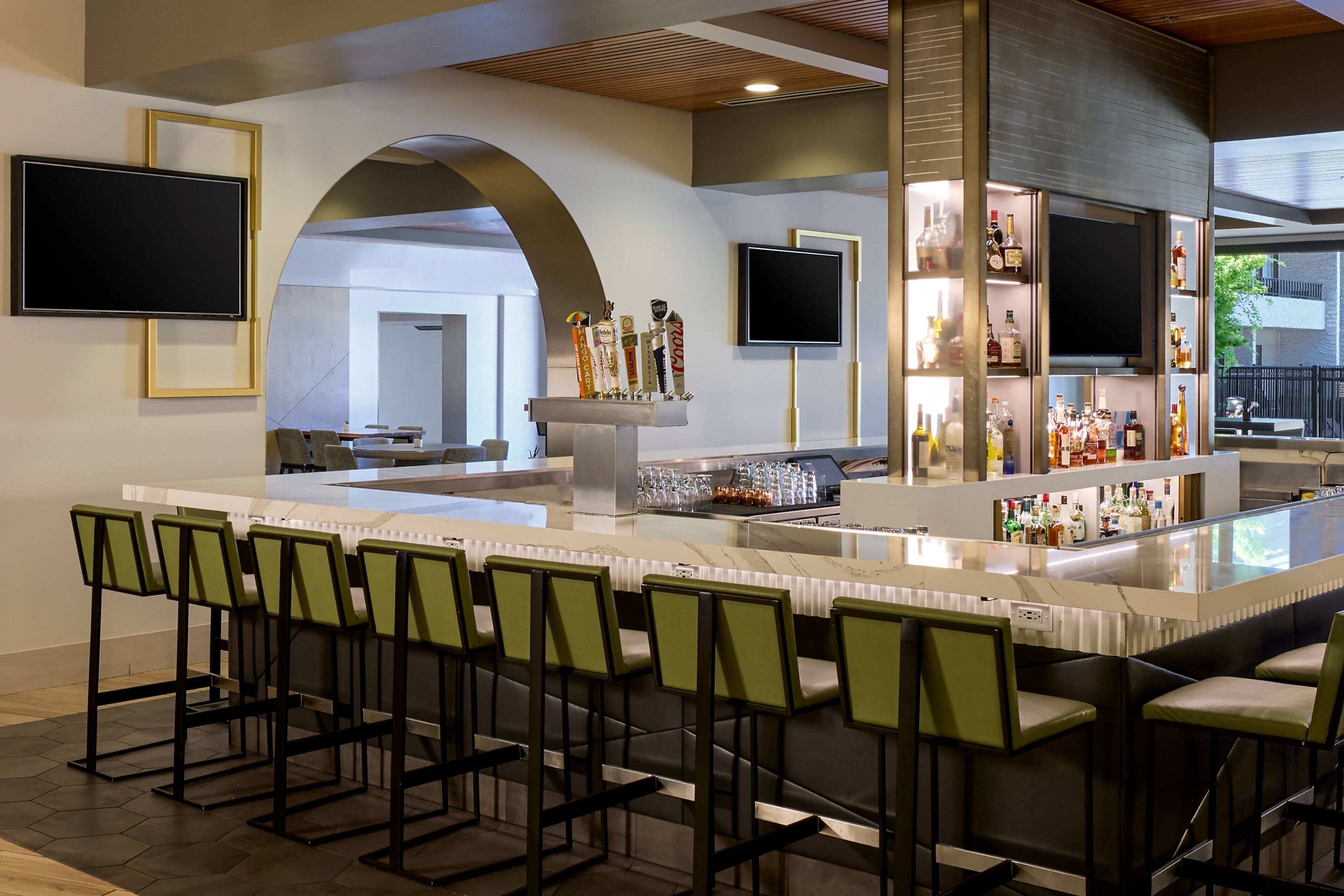 A bar area with multiple seating options and a television screen.