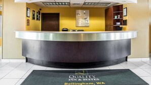 A hotel reception desk with a modern design, featuring a curved counter and a sign above it. - Quality Inn Grand Suites Bellingham (Bellingham)