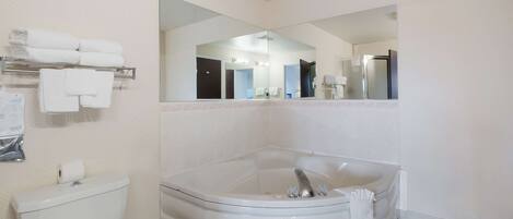 A modern bathroom with a large bathtub, a toilet, and a mirror.