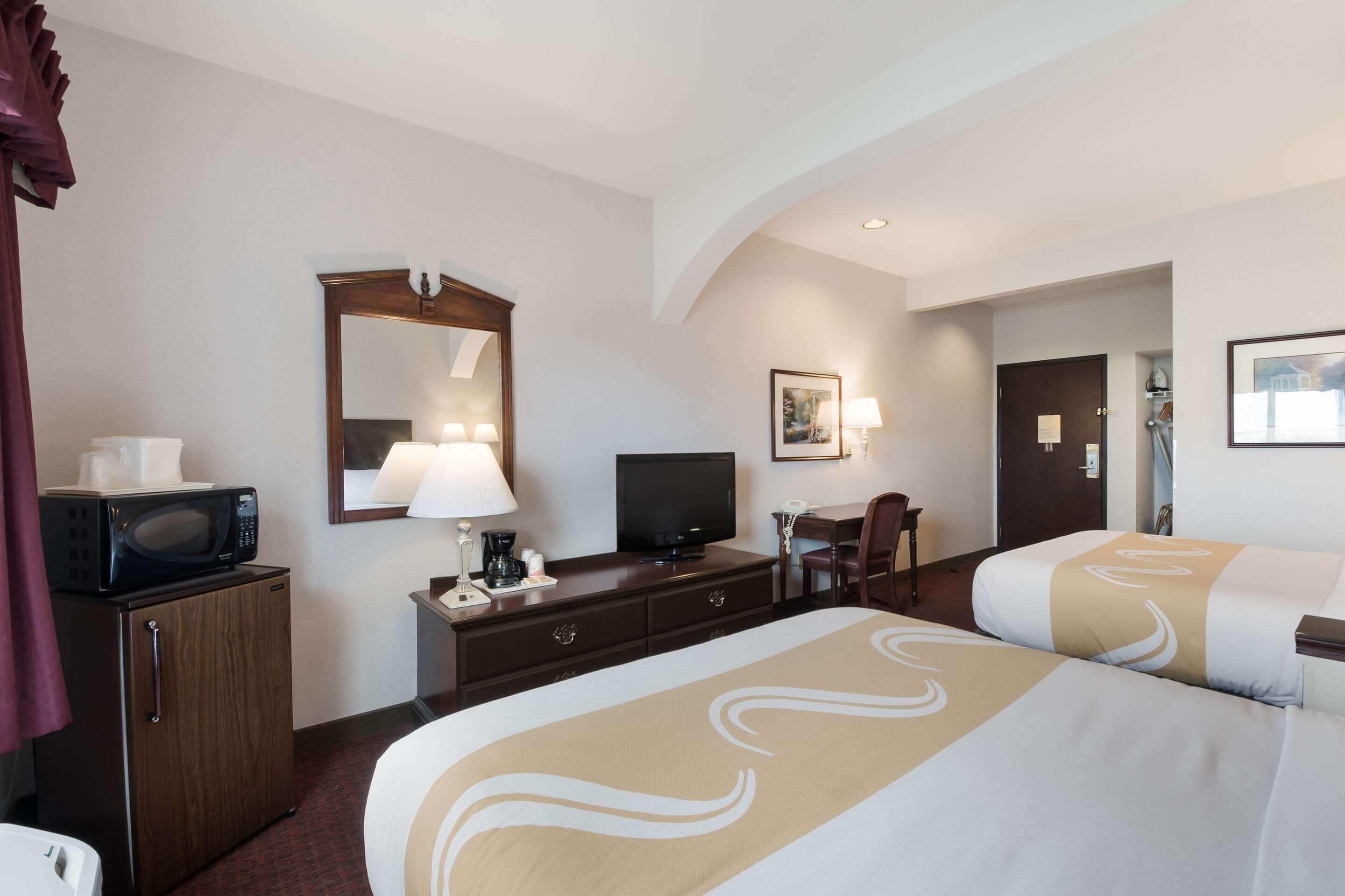 Una habitación de hotel con dos camas, televisor, escritorio y microondas.