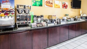 A breakfast bar with juice dispensers, coffee machines, and a flat-screen TV mounted on the wall.