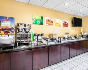 A breakfast bar with juice dispensers, coffee machines, and a flat-screen TV mounted on the wall.