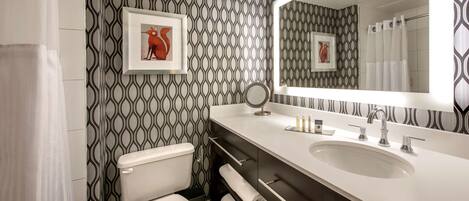 A modern bathroom with a patterned wallpaper, a large mirror, a sink, and a toilet.