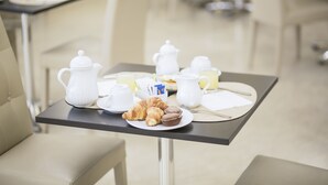 Una mesa con bollos, una tetera, tazas y una jarra.