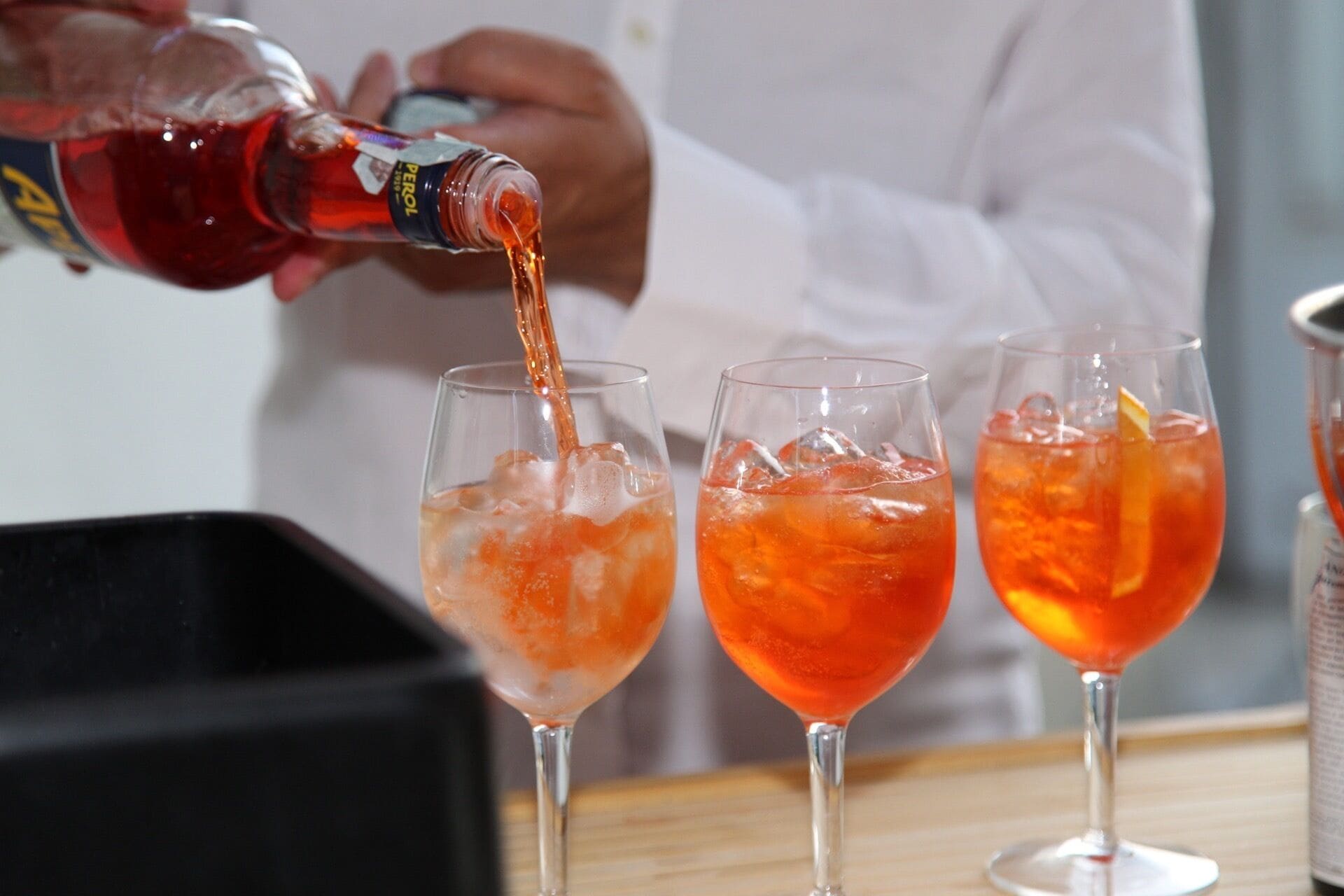 Una persona vertiendo un líquido rojo en tres vasos con hielo.
