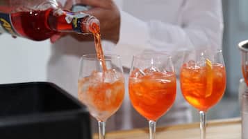 Una persona vertiendo un líquido rojo en tres vasos con hielo.