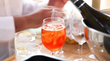 A bar setting with a bottle of champagne, a glass of red drink, and a glass of white drink with a lemon slice.