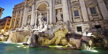 A grand building with a large fountain featuring statues and water jets.