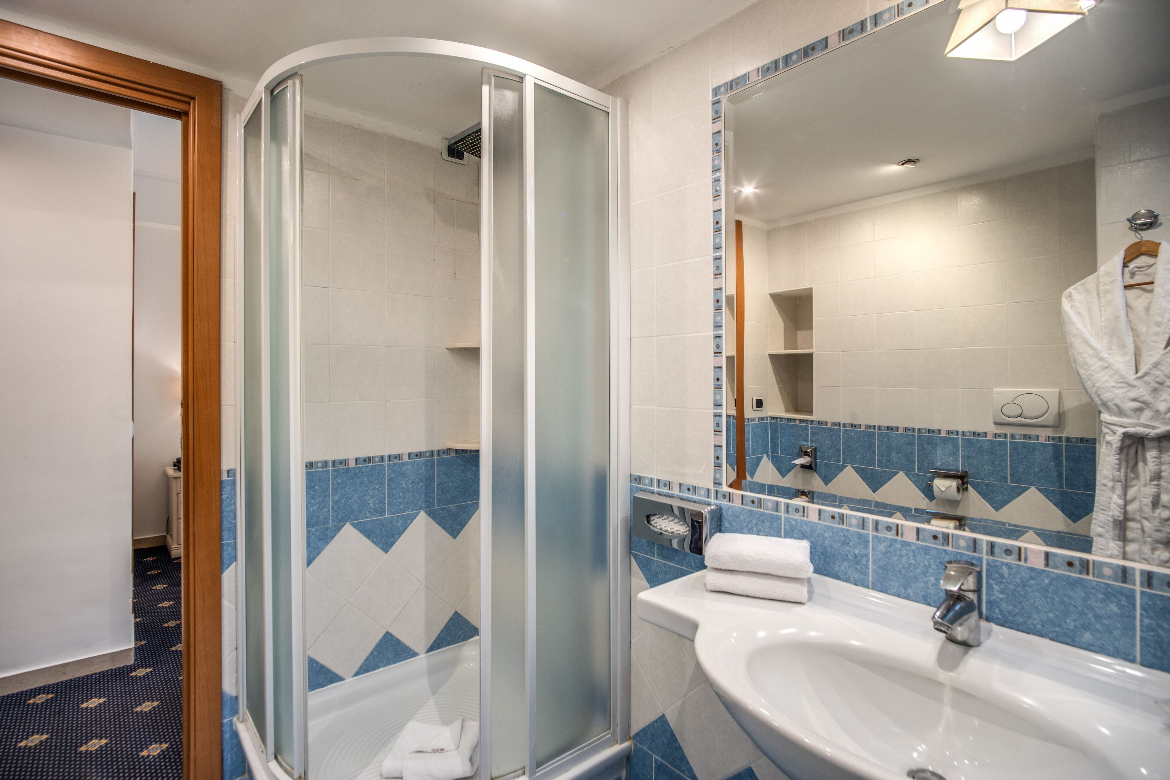 A bathroom with a glass-enclosed shower, a sink, and a mirror.