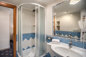 A bathroom with a glass-enclosed shower, a sink, and a mirror.