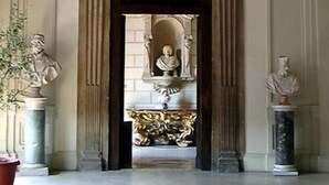 Un arco empotrado con detalles arquitectónicos clásicos, flanqueado por estatuas y un relieve decorativo.