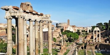 Ancient ruins with columns and a large amphitheater in the background.