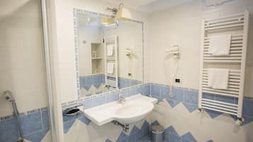 A bathroom with a sink, mirror, towel rack, and shower.