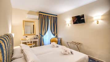 Una camera d'albergo con un letto, una scrivania, una sedia, uno specchio e una TV a parete.