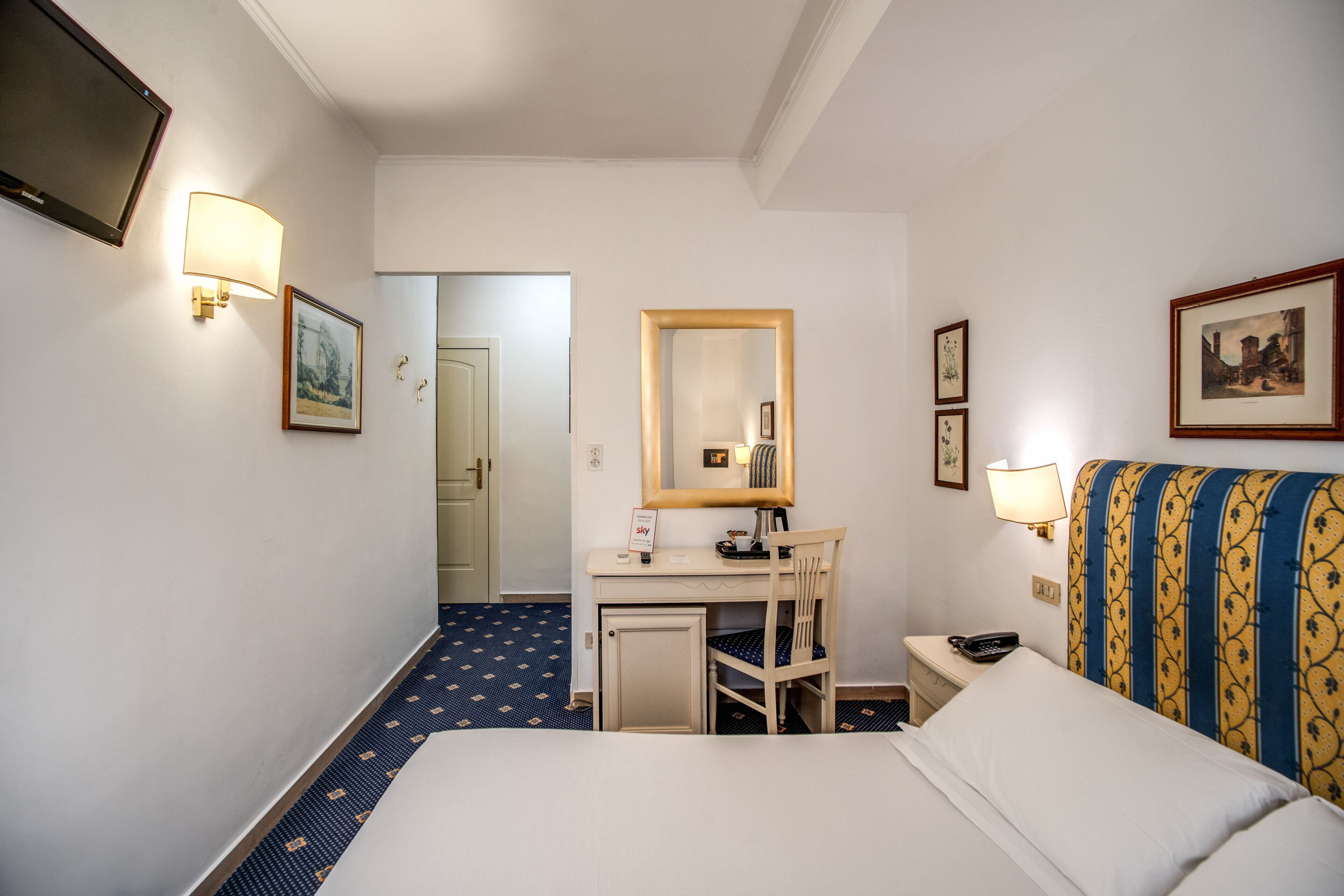Een hotelkamer met een bed, bureau, stoel en een kleine bureaulamp.