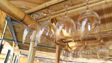 Copas de vino colgadas de una estructura de techo de bambú.