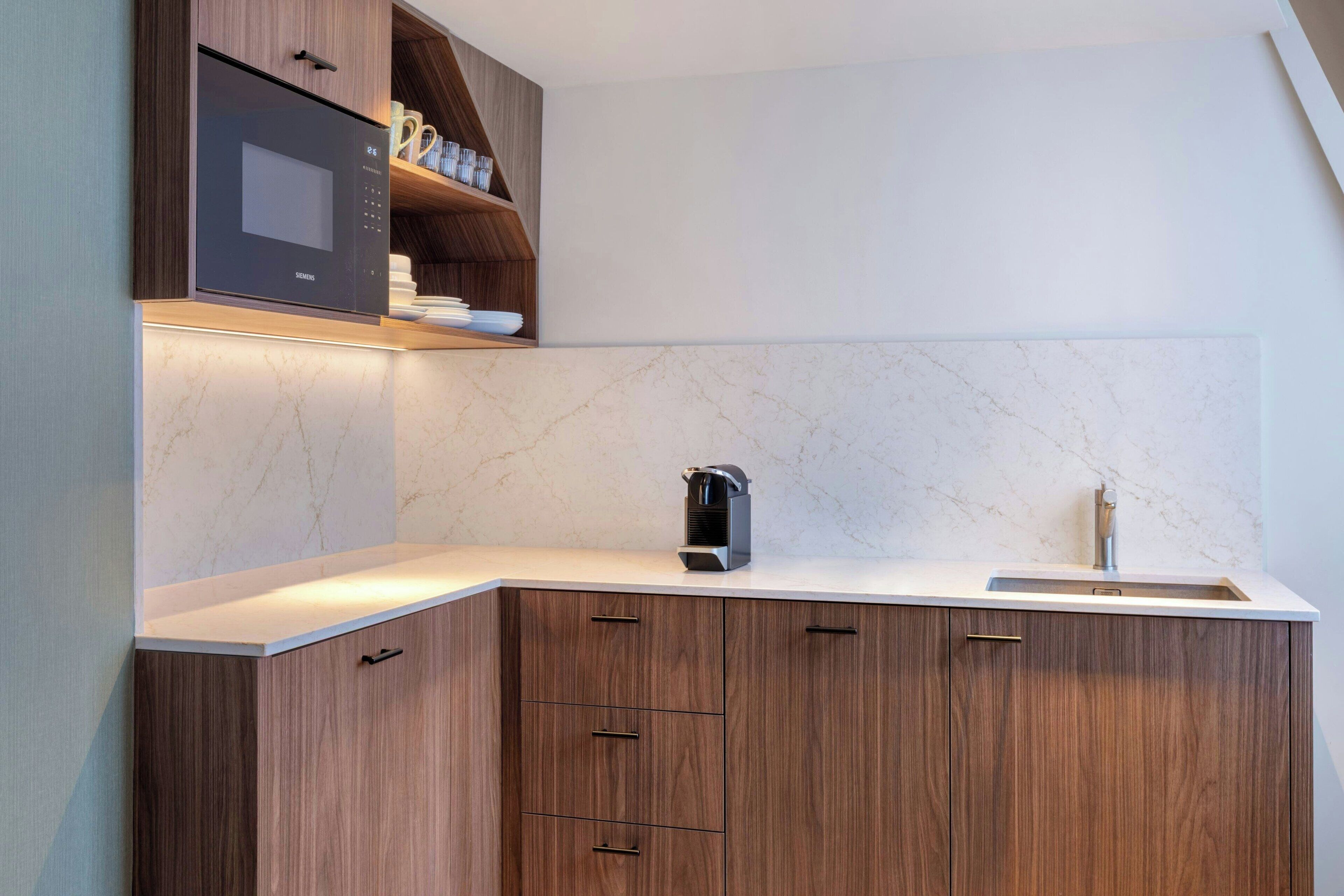 Een moderne keuken met een ingebouwde magnetron, een waterkoker en een spoelbak.