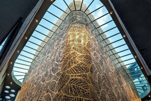 A modern building with a unique, intricate facade and a glass ceiling allowing natural light to enter.