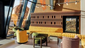 A modern interior with a seating area featuring yellow upholstered sofas and chairs, a decorative wall panel, and a view of a dome through large windows.