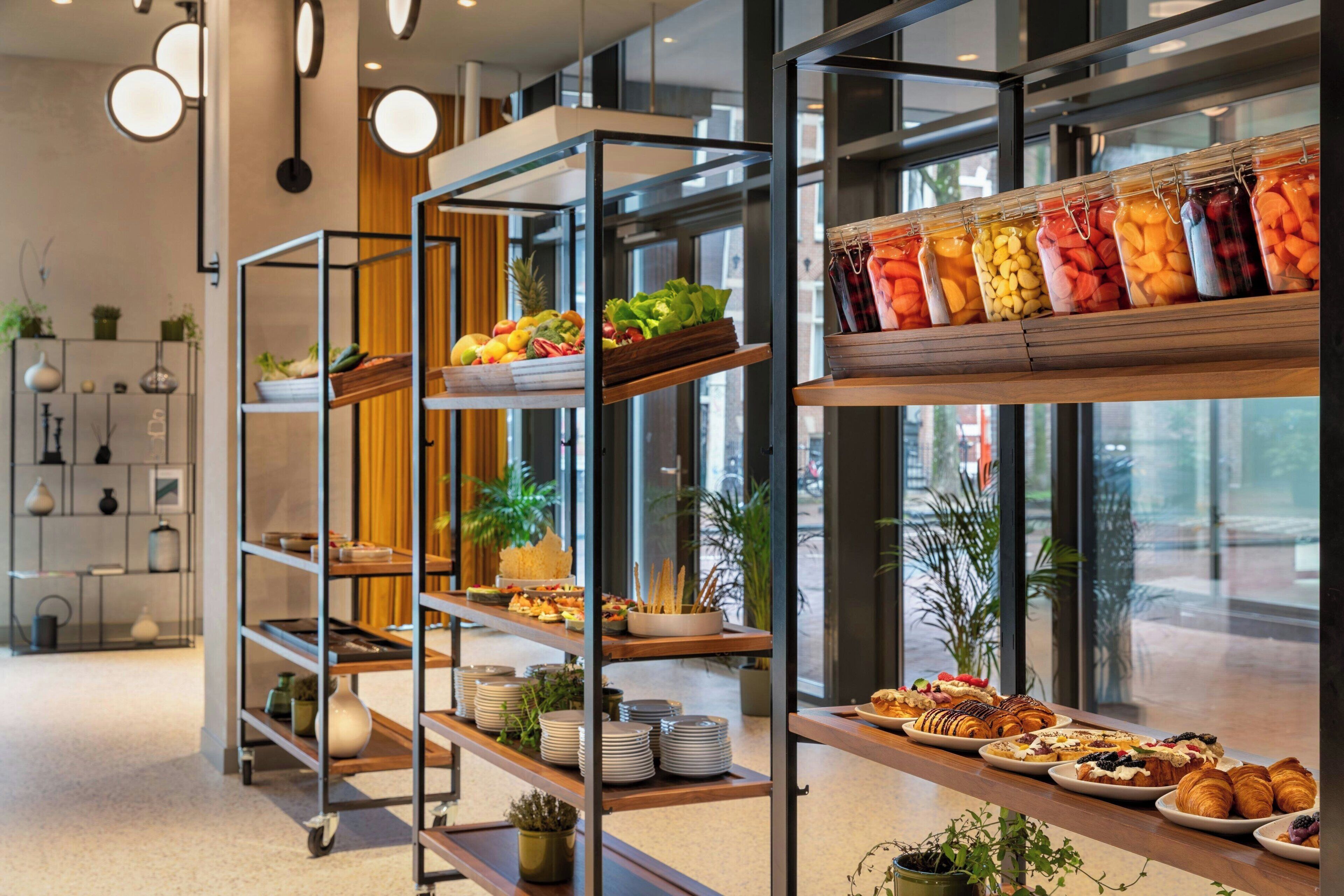A modern interior with a buffet setup, including various food items and decorative plants.