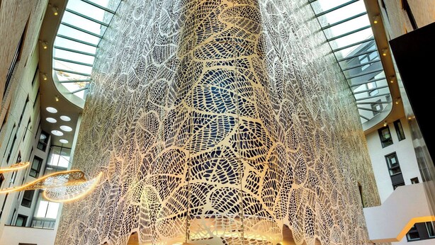 A spacious lobby with a high ceiling and a large, intricate light installation.