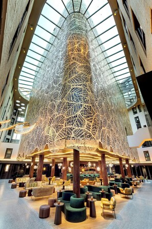 A spacious lobby with a high ceiling and a large, intricate light installation. - Renaissance Amsterdam Hotel (Amsterdam)