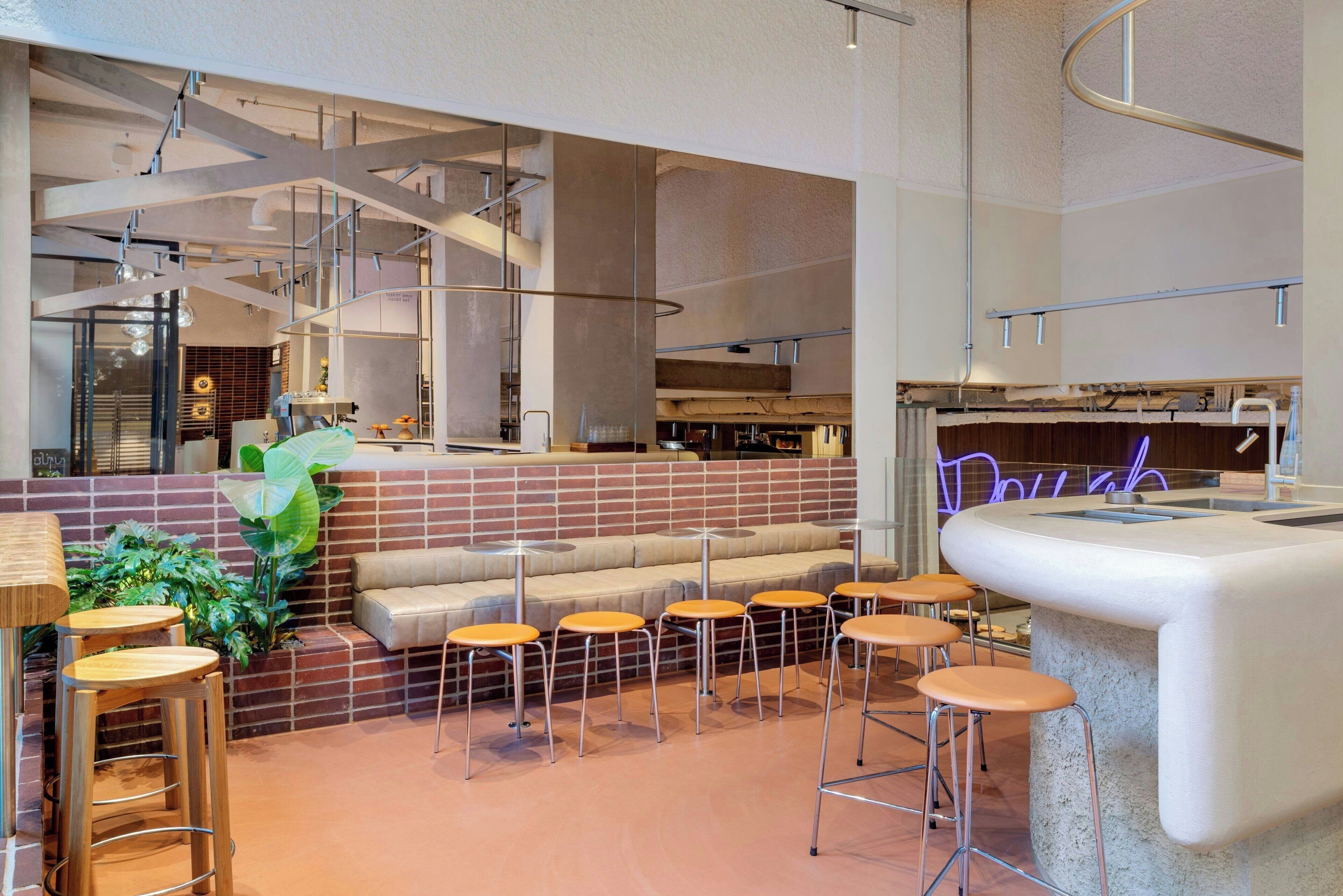 Een modern interieur met een bakstenen muur, een zithoek met krukken, en een bar.