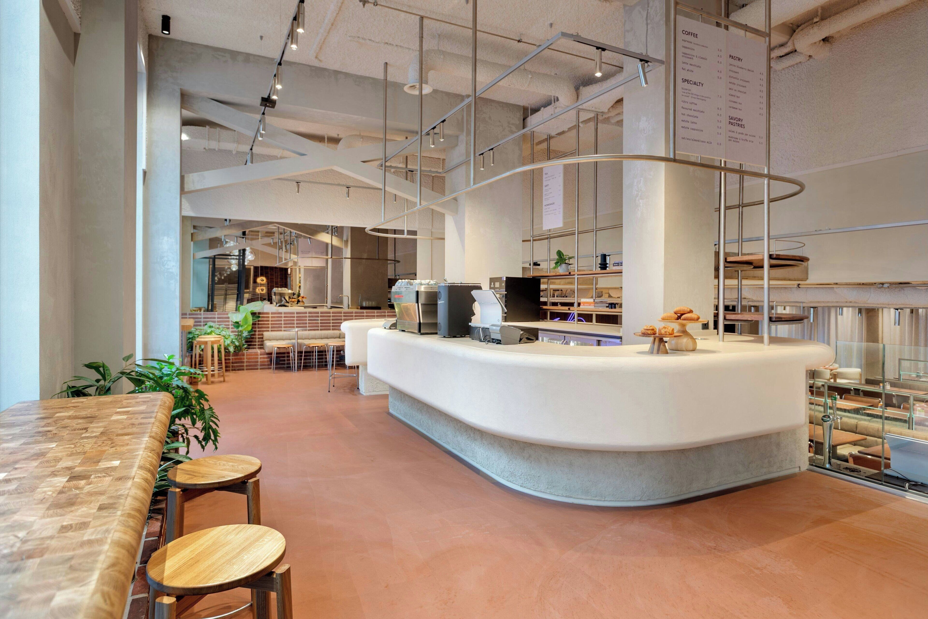 A modern cafe with a curved counter, seating area, and visible menu boards.