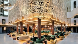 A spacious lobby with modern seating arrangements, a bar area, and a distinctive ceiling design.