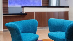 A reception area with two blue chairs, a wooden reception desk, a map on the wall, and a clock. - Fairfield Inn & Suites by Marriott Temple Belton (Temple)