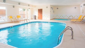 An indoor swimming pool with clear blue water, surrounded by yellow and white lounge chairs, and a tiled floor. - Fairfield Inn & Suites by Marriott Temple Belton (Temple)