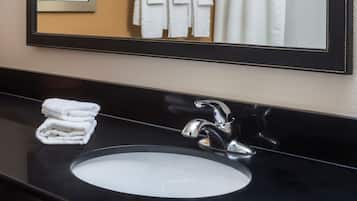 A bathroom with a black countertop, a white sink, and a mirror with a black frame.