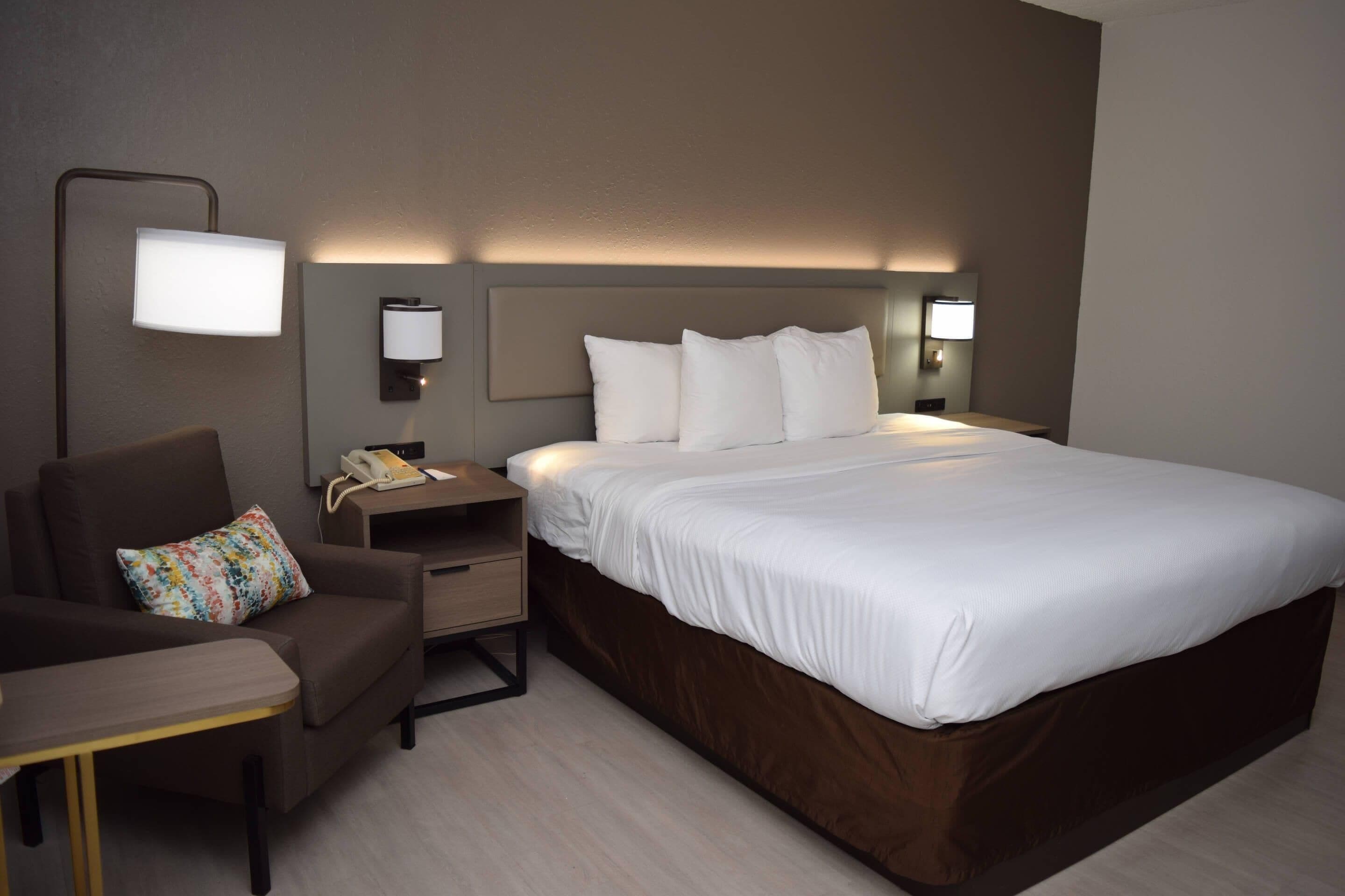 Une chambre d’hôtel avec un grand lit, un bureau, une chaise et des lampes de chevet.